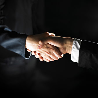 Business handshake close-up on dark background