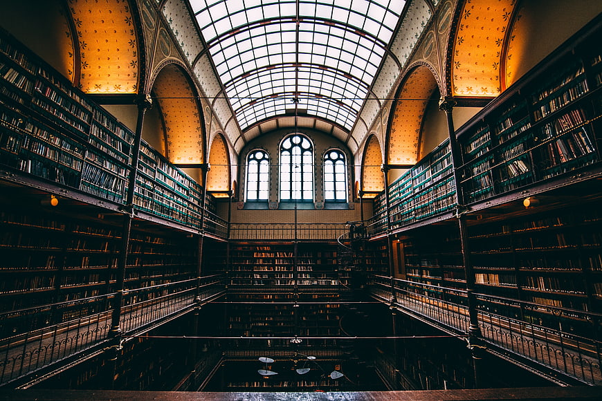 Grand historic library interior with glass ceiling and bookshelves