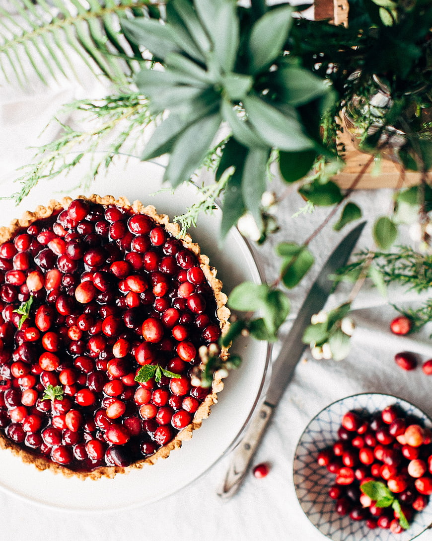 Overhead view of cranberry tart with fresh berries and greenery