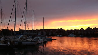 Sunset over marina with sailboats and waterfront homes