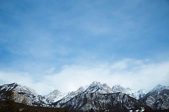 Snow-Capped Mountain Range Under Blue Sky with Clouds