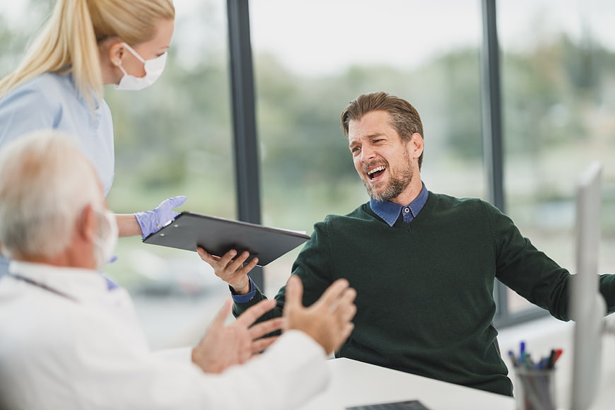 Upset male patient arguing with doctor and nurse in clinic