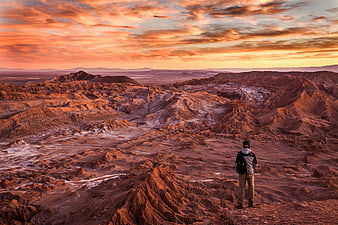 Man overlooking vast desert landscape at sunset