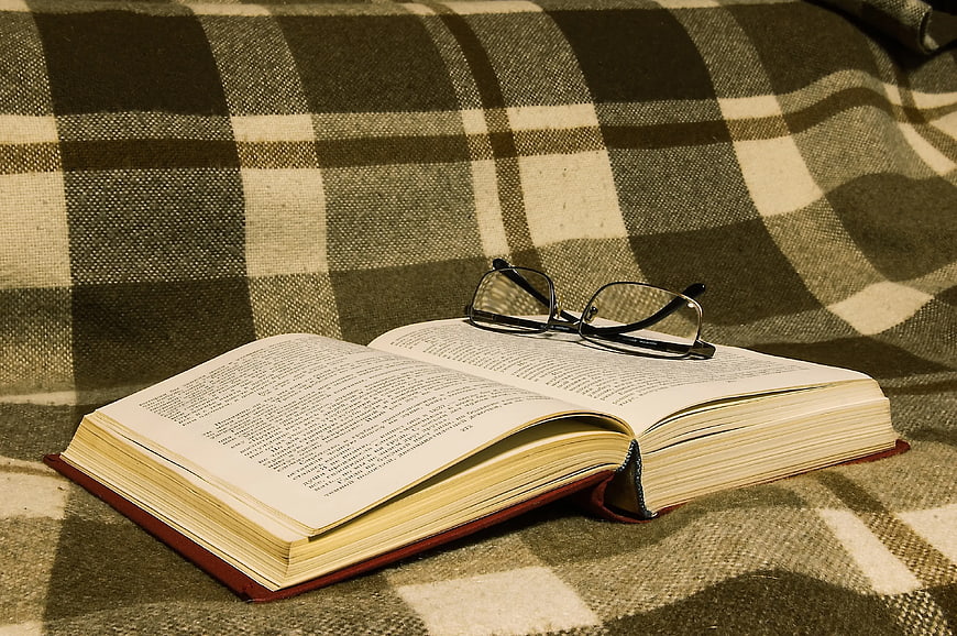 Open Book with Glasses on Plaid Blanket