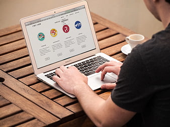 Man typing on MacBook Air laptop at wooden table