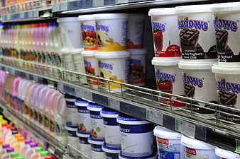 Supermarket shelves stocked with various yogurt brands and dairy products