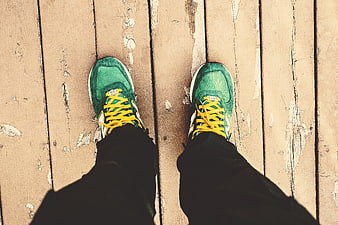 Green Sneakers with Yellow Laces on Wooden Deck