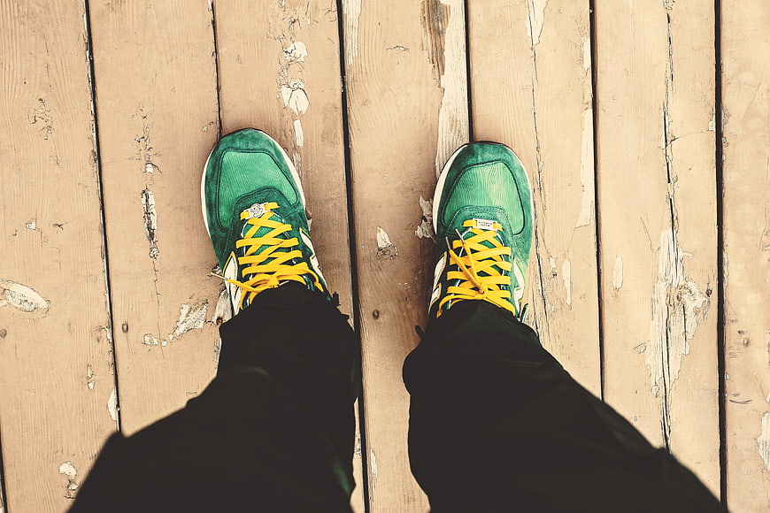 Green Sneakers with Yellow Laces on Wooden Deck