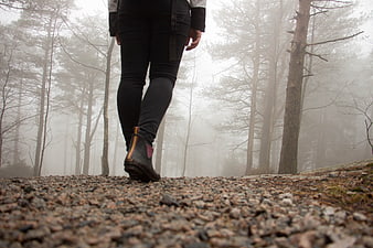 Hiker walking on gravel path in foggy forest