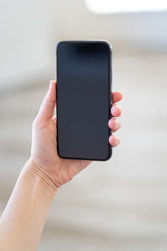 Hand holding smartphone with blank black screen