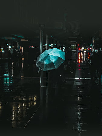 Person with Blue Umbrella on Rainy City Street at Night
