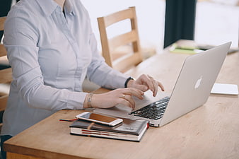 Professional Woman Typing On Silver Laptop At Wooden Desk