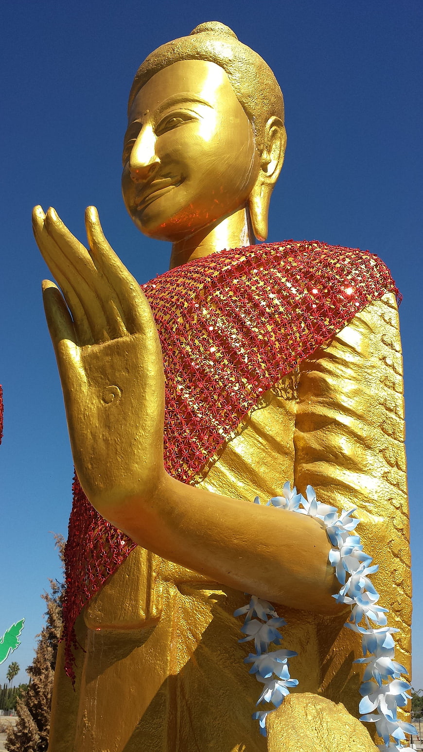 Golden Buddha Statue with Red Robe and Blue Sky Background