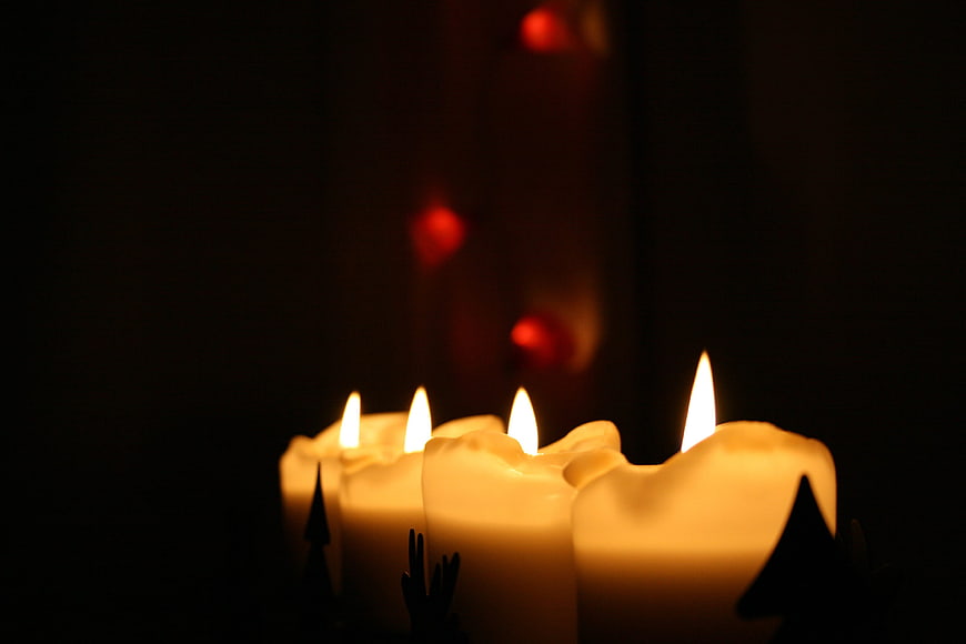 Advent candles with tree silhouettes in dark setting