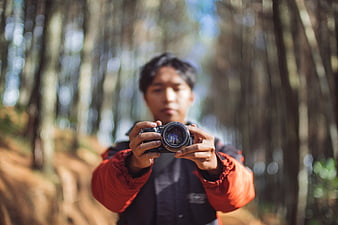Man holding camera in forest with shallow depth of field