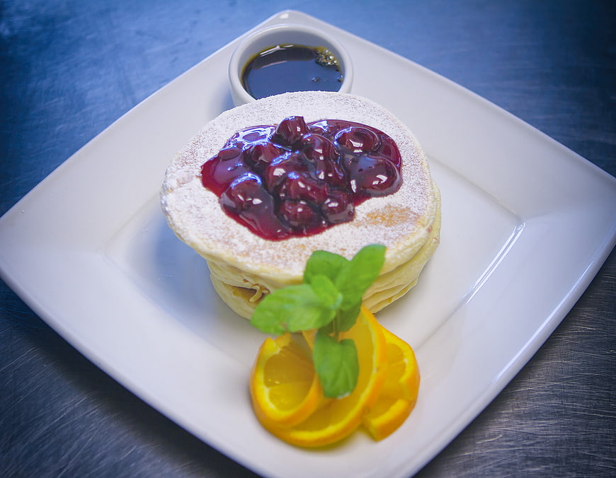 Stack of pancakes with berry sauce and orange slices