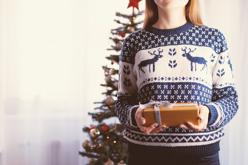Woman in Christmas Sweater Holding Gift Box Near Tree