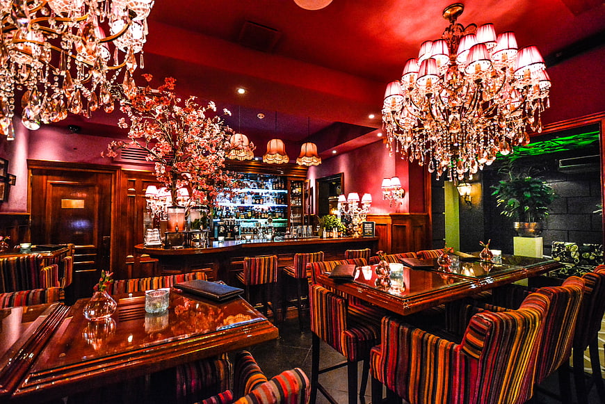 Luxurious Hotel Bar Interior With Crystal Chandeliers And Red Lighting