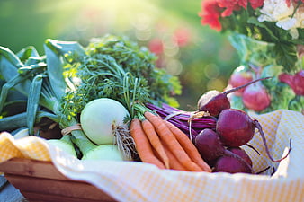 Fresh organic vegetables in a wooden basket with checkered cloth