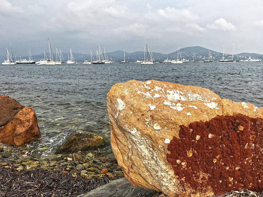 Rocks on Mediterranean Shore with Sailboats in Background