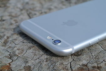 Close-up of silver iPhone 6 back camera and Apple logo on cracked wood
