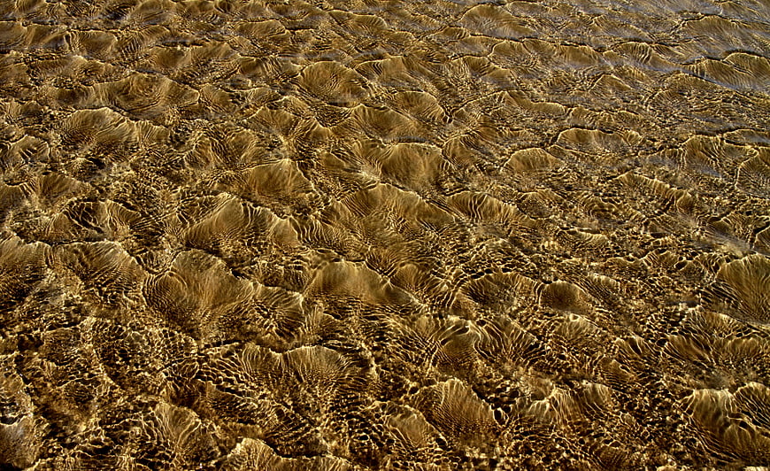 Golden Sand Texture Under Shallow Water Surface