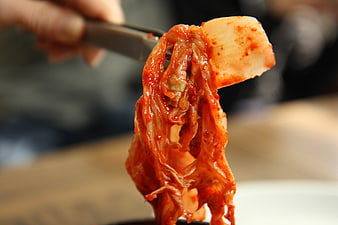 Close-up of spicy kimchi held by chopsticks