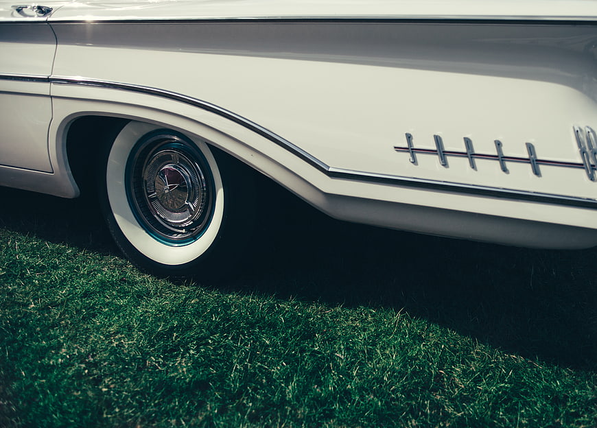 Close-up of vintage white car wheel on grass