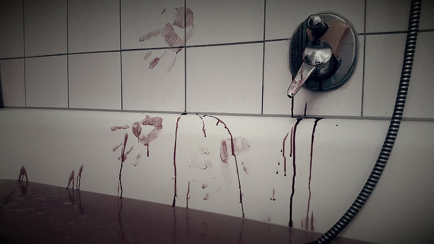 Bloody handprints and dripping blood on white bathroom tiles