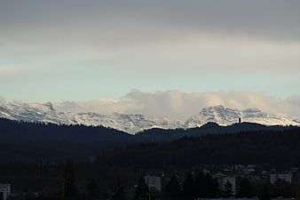 Snow-capped mountain range with dark forest foreground