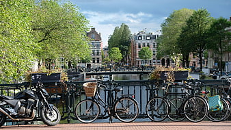 Bicycles and Motorcycle Parked on Amsterdam Canal Bridge
