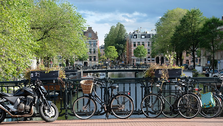 Bicycles and Motorcycle Parked on Amsterdam Canal Bridge