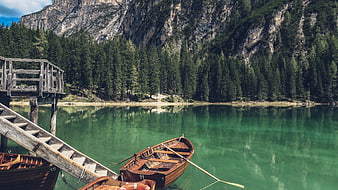 Wooden boats docked at a serene alpine lake with mountain reflections