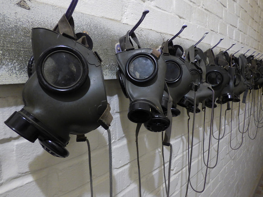 Row of vintage gas masks hanging on a white brick wall