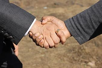 Close-up of two men shaking hands outdoors in business attire