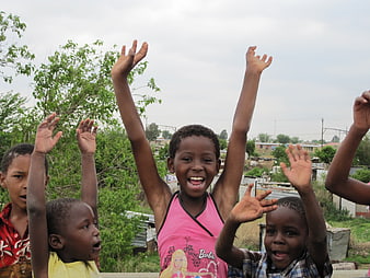 Happy African children cheering with raised hands outdoors