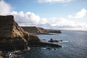 Dramatic coastal cliffs meeting the ocean under a cloudy sky