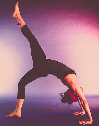 Woman performing advanced yoga backbend pose on purple mat