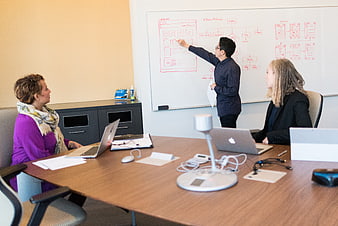 Team brainstorming web design wireframes on whiteboard in office