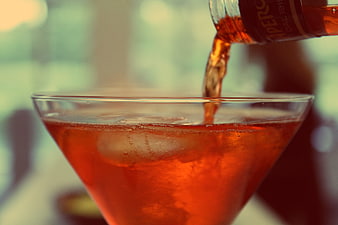 Amaro being poured into a cocktail glass with ice