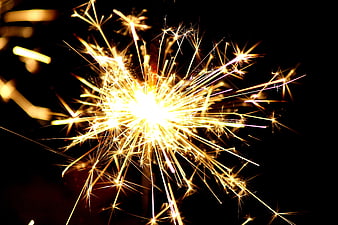 Bright Golden Sparkler Burning Against Black Background