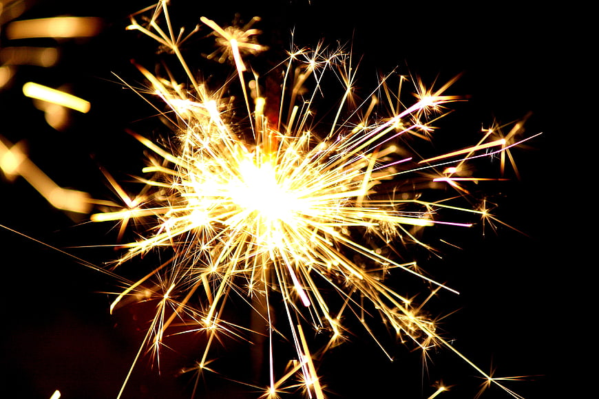 Bright Golden Sparkler Burning Against Black Background