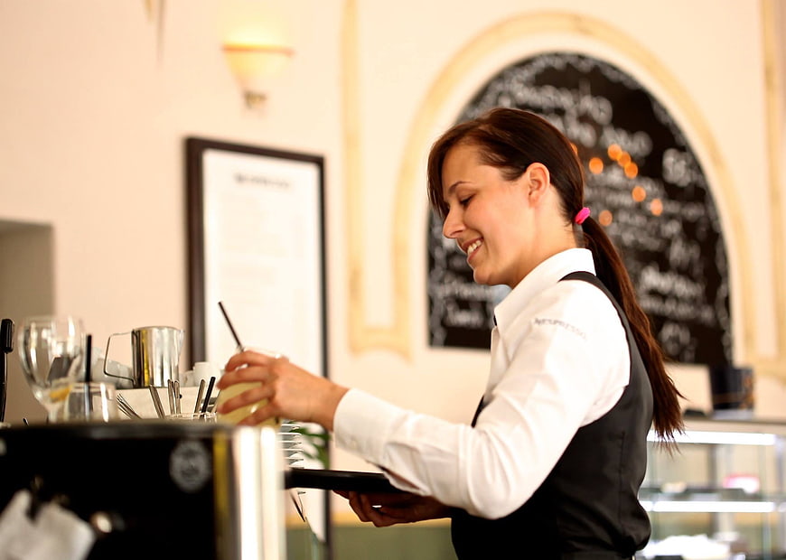 Smiling waitress preparing a drink in a cafe