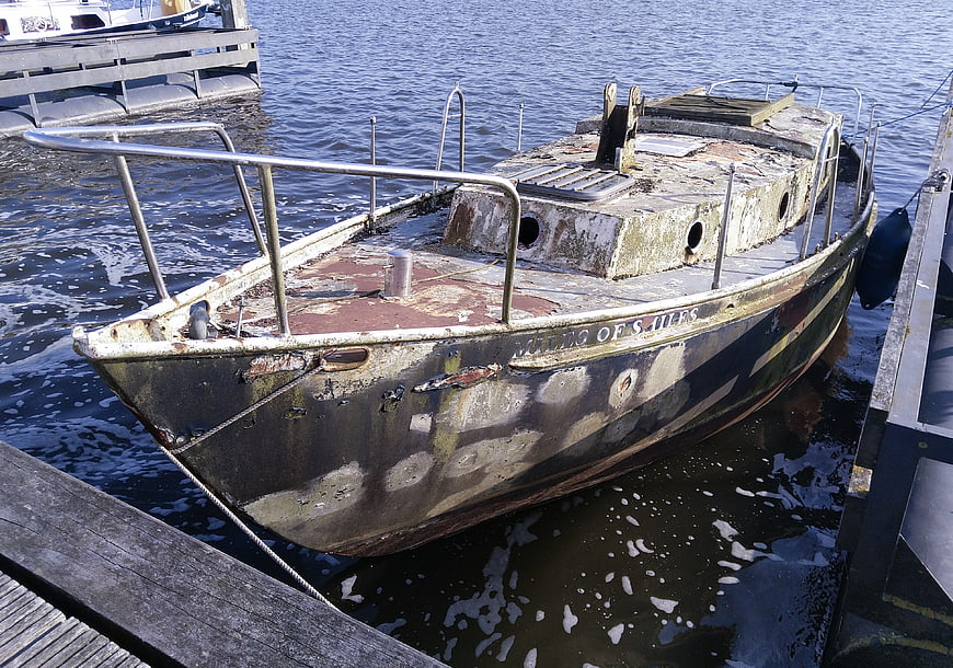 Weathered wooden boat docked at a marina pier