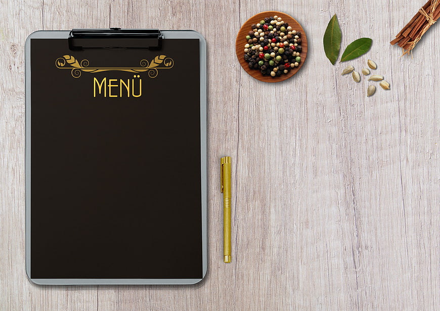 Restaurant Menu Clipboard with Spices and Pen on Wood