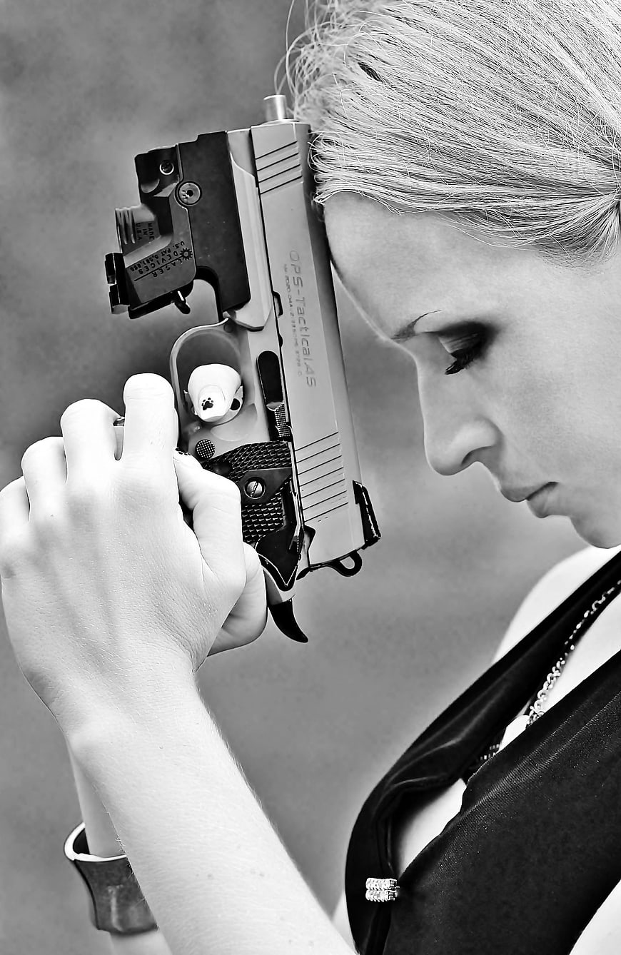 Black and white portrait of a woman holding a pistol to her head