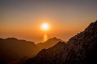 Golden Sunset Over Rocky Mountain Peaks and Ocean Horizon