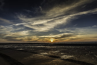 Dramatic sunset over wet tidal flats with clouds