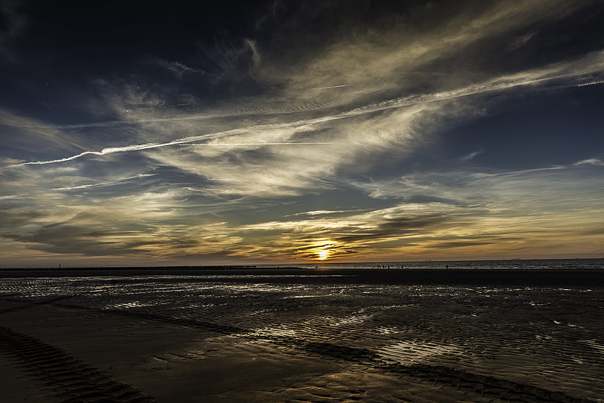 Dramatic sunset over wet tidal flats with clouds