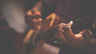 Close-up of hands playing acoustic guitar in warm light
